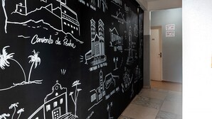 Un couloir avec un mur noir orné de dessins blancs représentant des monuments célèbres et comportant du texte.