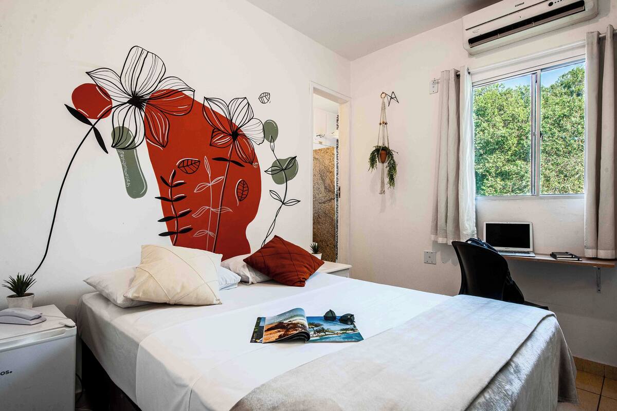 A neatly arranged bedroom with a bed, a desk, and a window with a view of trees.