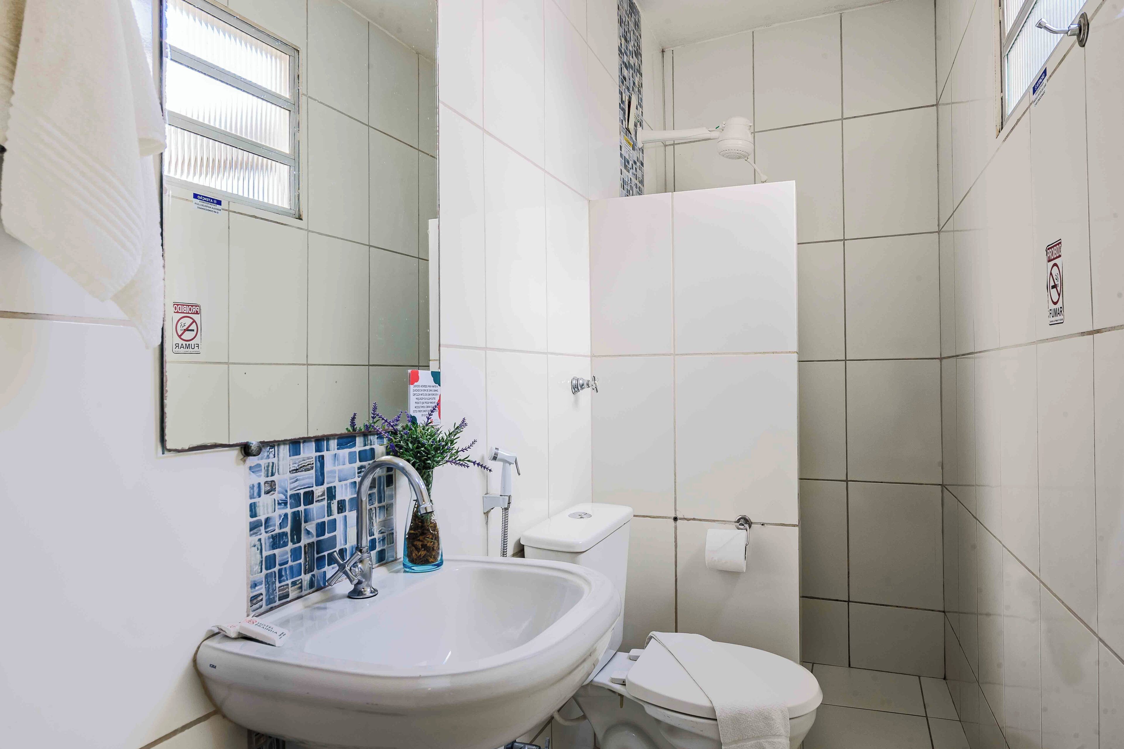 Un baño con lavamanos, inodoro y ducha blancos.
