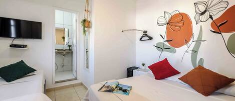 Habitación de hotel con una cama, un televisor montado en la pared y un baño visible a través de una puerta abierta.