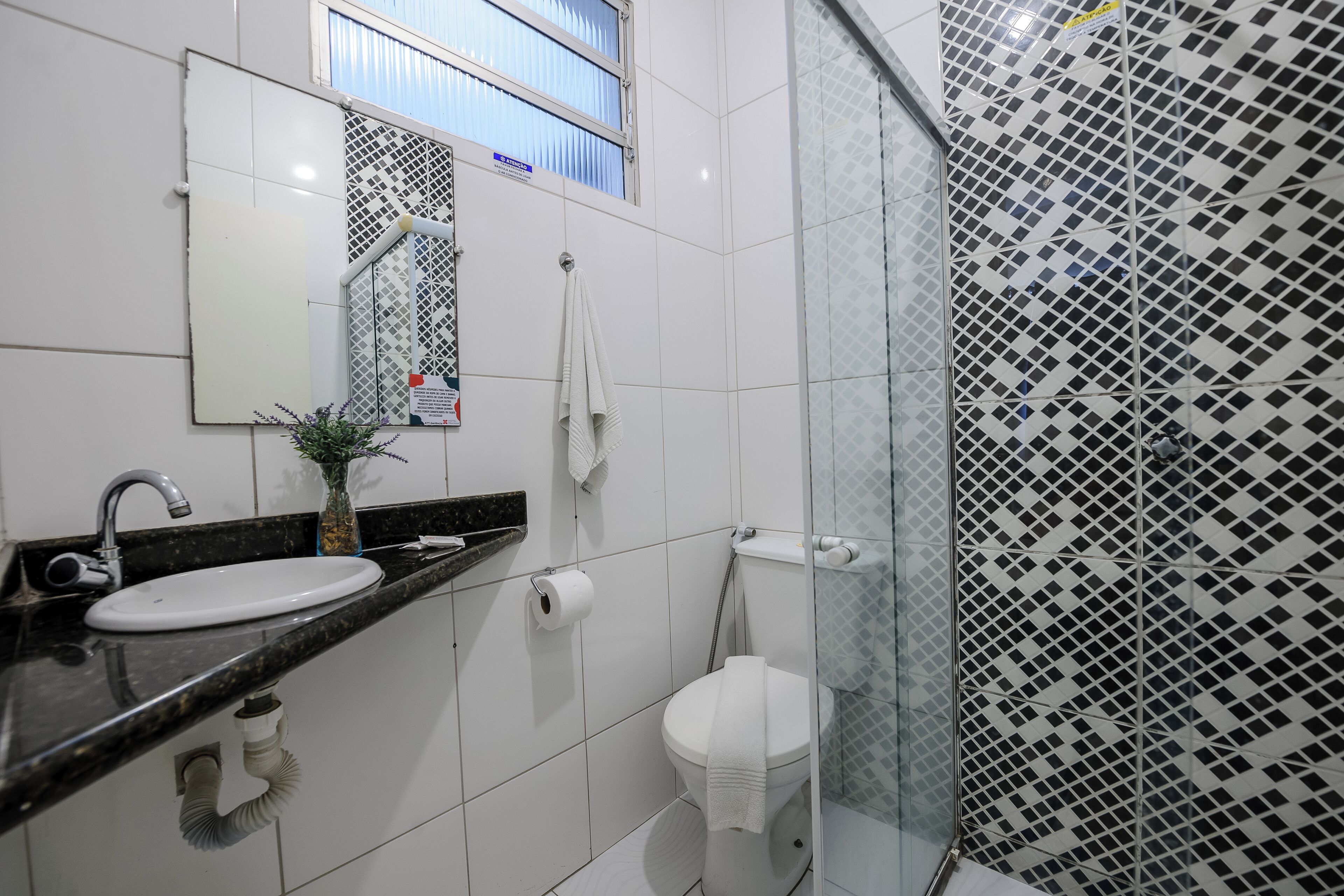A bathroom with a white sink, mirror, and toilet.