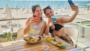 Two people taking a selfie at a table with a view of the beach and ocean. - Casa Andina Select Paracas (Paracas)