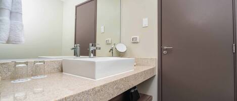 Un baño moderno con un espejo grande, un lavabo blanco y un perchero para toallas.