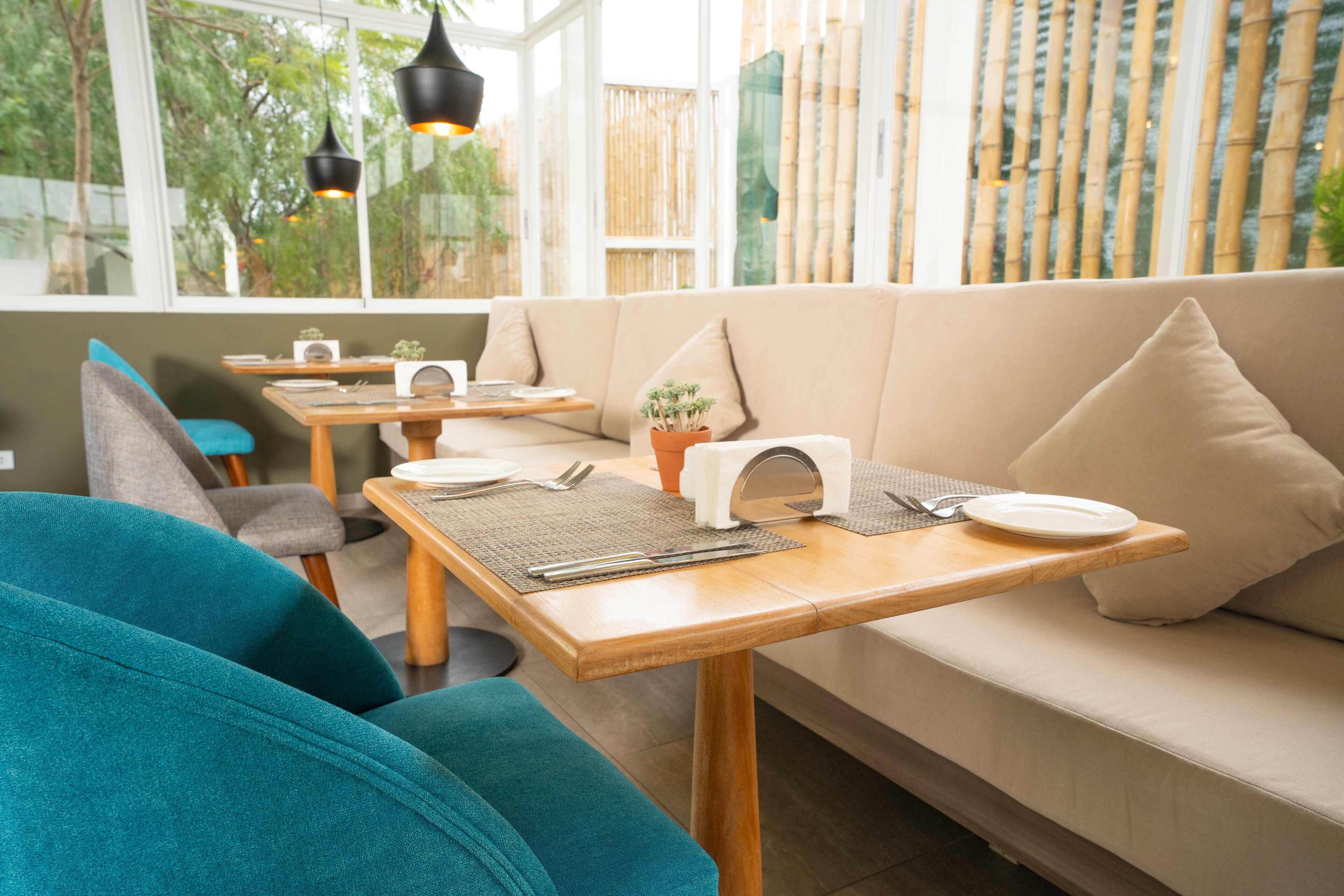 A cozy dining area with a sofa, wooden tables, and chairs.