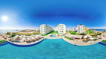 A resort with a central pool, multiple buildings, and a beach area.