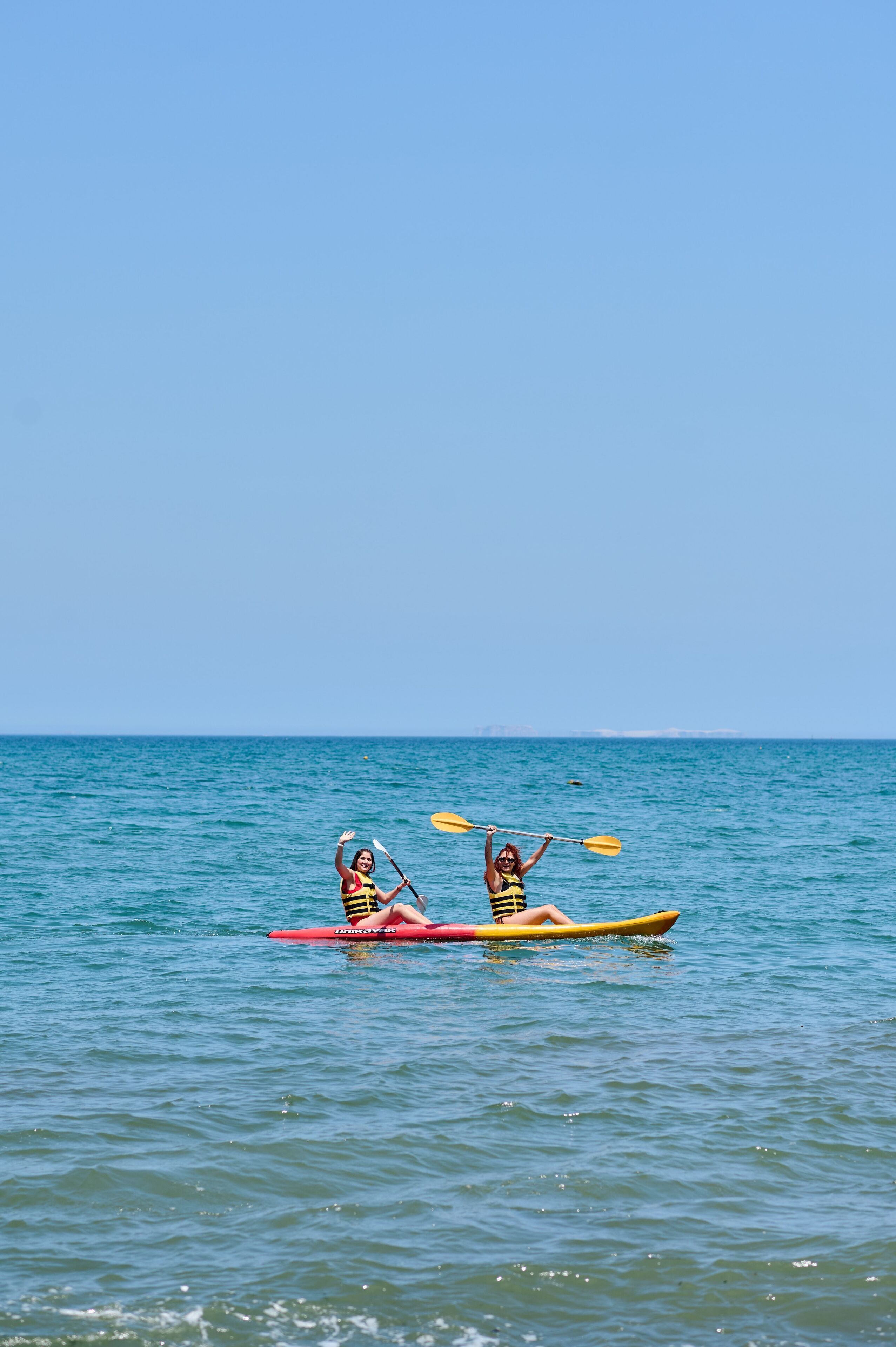 Two people kayaking on a calm sea.