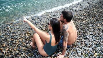 Privat strand, hvit sand, solsenger og parasoller