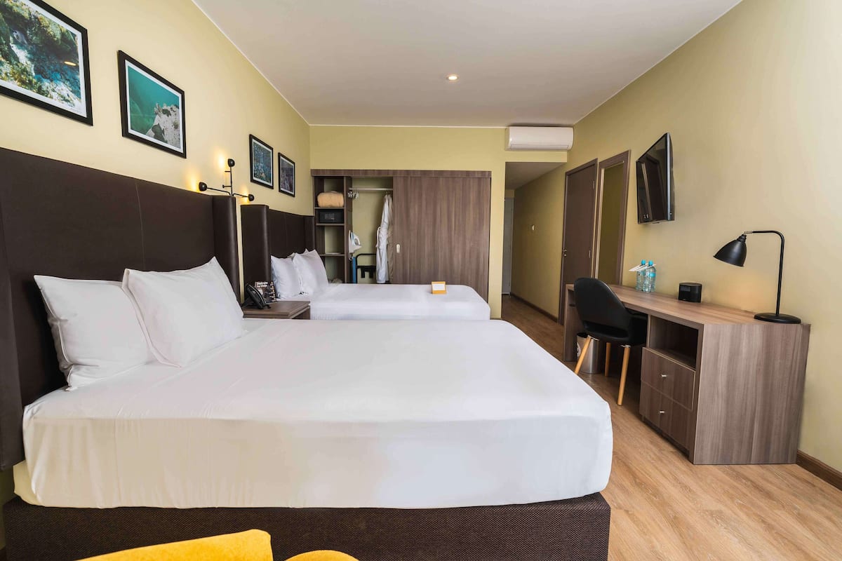 A hotel room with a large bed, a desk, a chair, a wardrobe, and a TV.