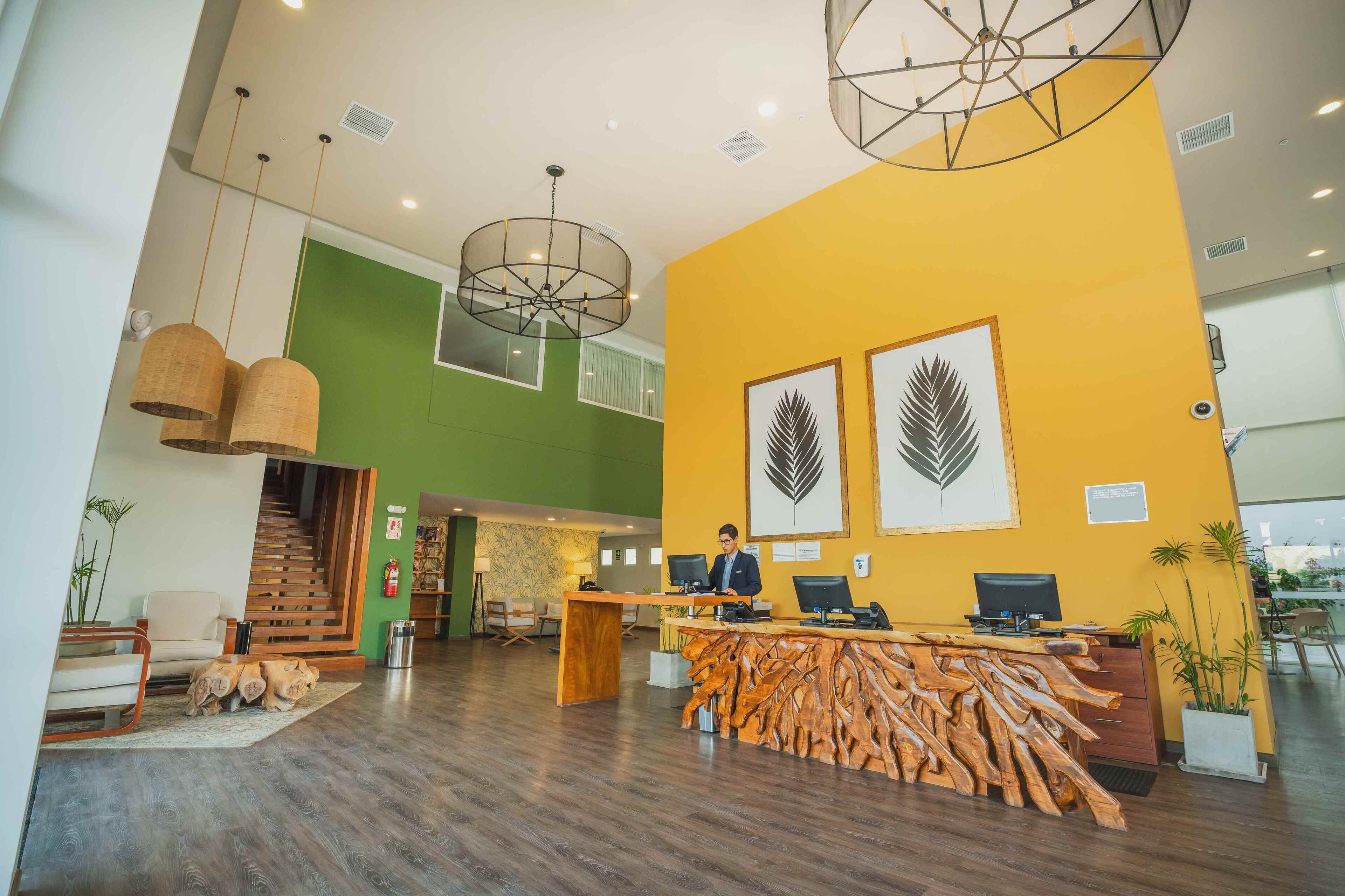 A reception area with a wooden reception desk, two computer monitors, and a person seated behind it.