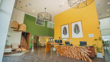 A reception area with a wooden reception desk, two computer monitors, and a person seated behind it.