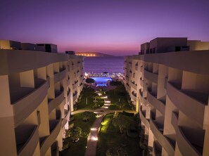 A hotel courtyard at dusk with a pool and lounge area, surrounded by modern buildings. - Casa Andina Select Paracas (Paracas)