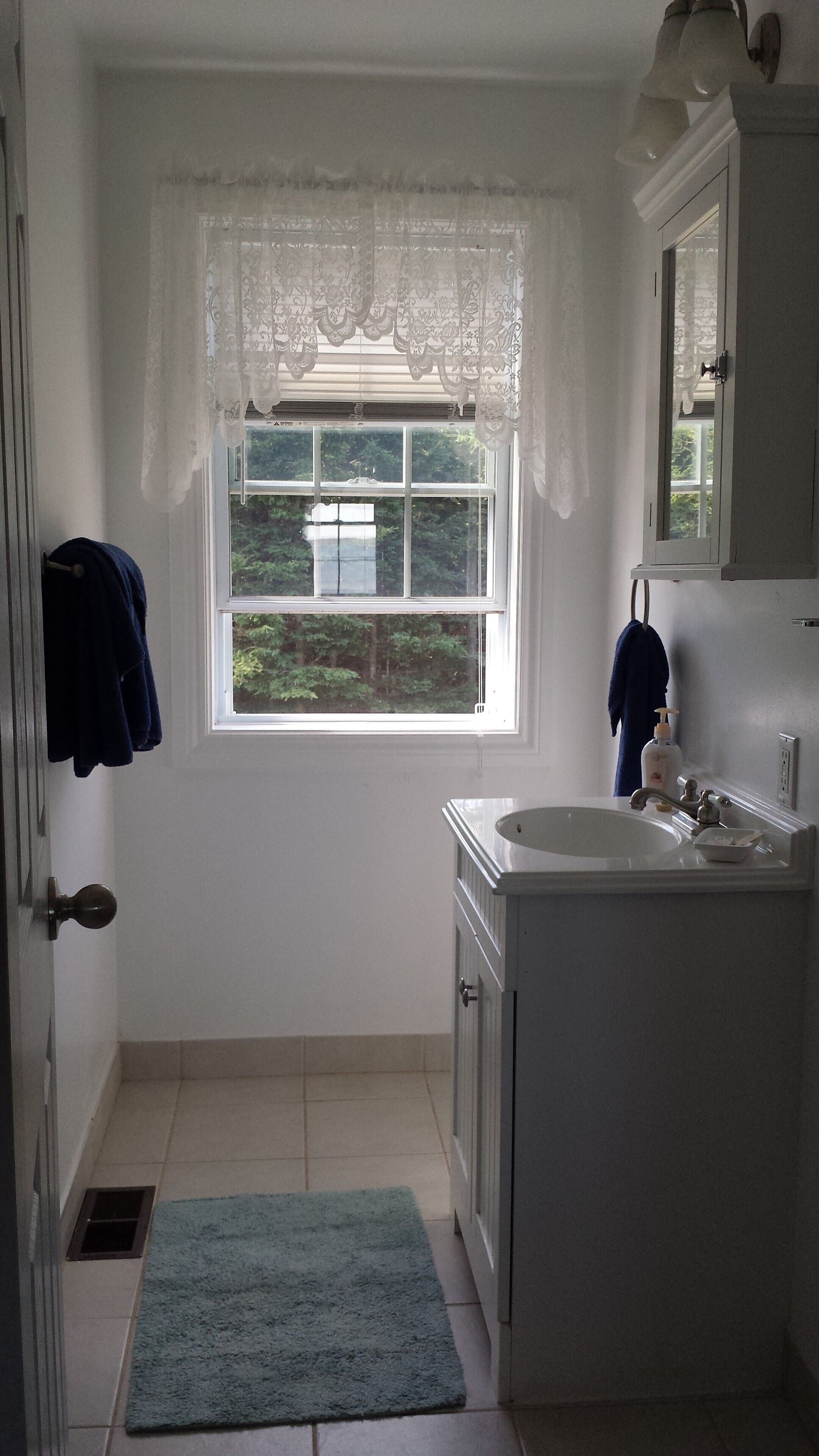 A bathroom with a window, a sink, and a towel rack.
