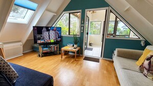 Una sala de estar acogedora con televisión, sofá, mesa de centro y estantería.