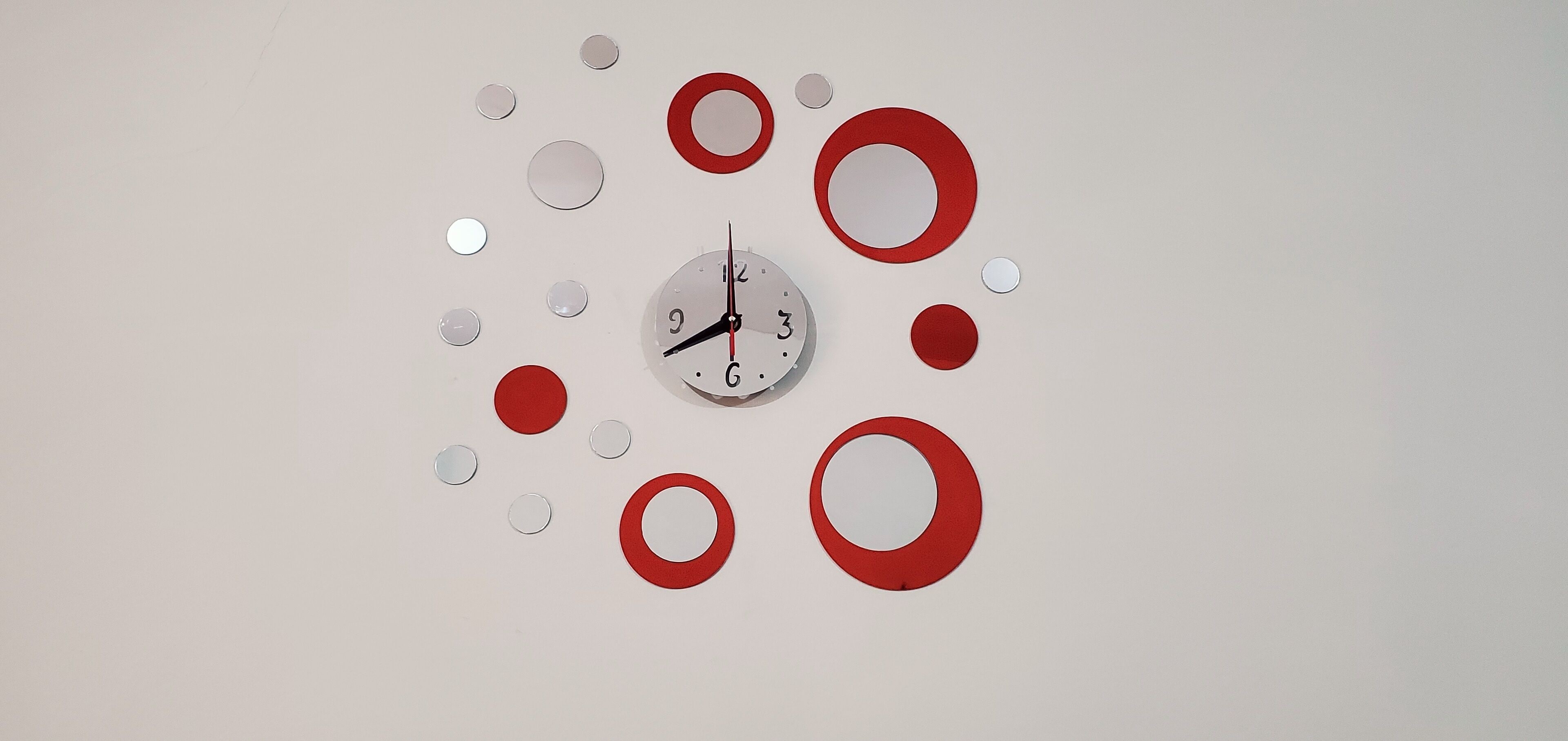 A wall clock with a minimalist design, surrounded by evenly spaced circular decorations.