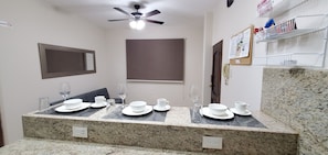Bagno con piano in granito, più lavabi, ventilatore a soffitto, specchio, bacheca e una porta.