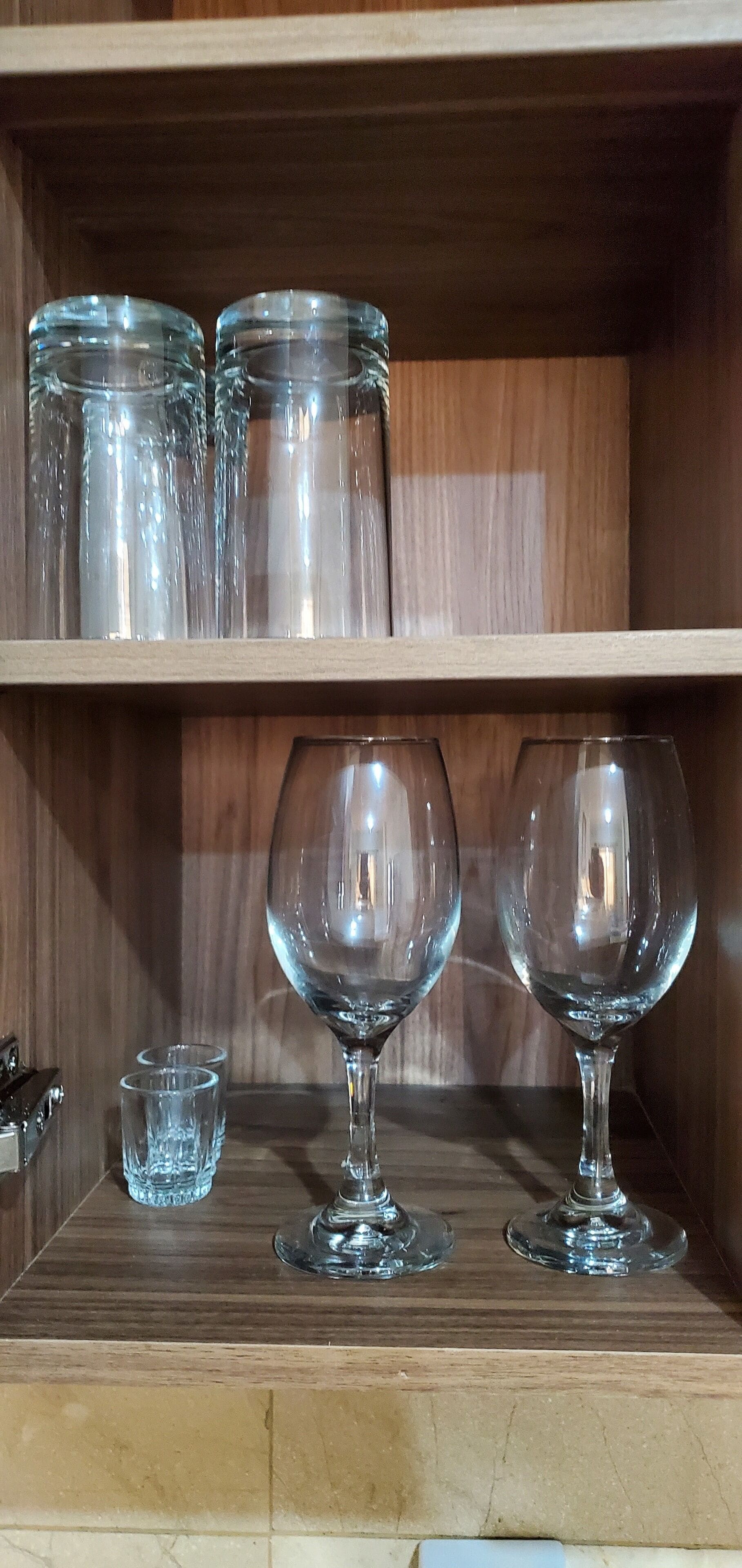 Una estantería de madera con frascos de vidrio y copas de vino.