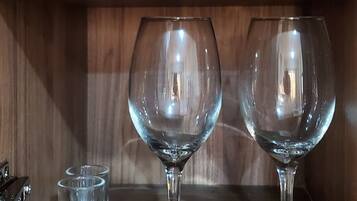 Una estantería de madera con frascos de vidrio y copas de vino.