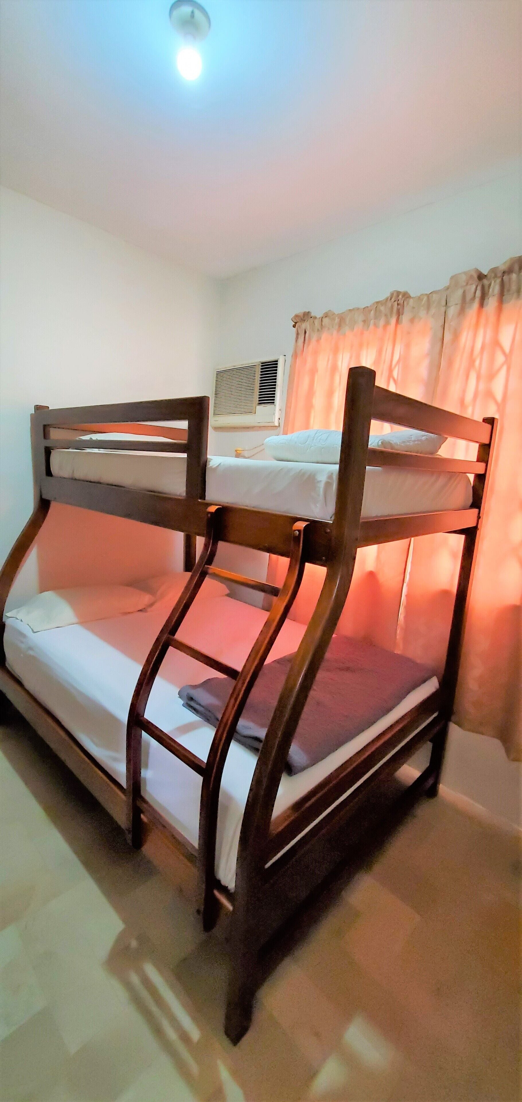 Uma cama beliche com estrutura de madeira e roupa de cama branca.