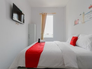 Een slaapkamer met een bed, een aan de muur bevestigde televisie, een raam met gordijnen en een decoratie aan de muur.
