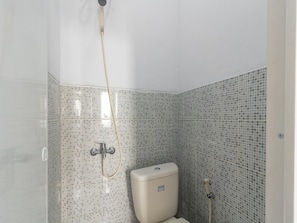 Een kleine badkamer met toilet, douche en betegelde wanden.