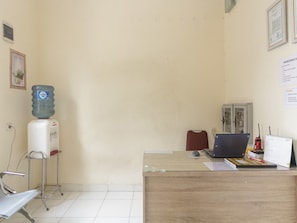 Een receptiebalie met een laptop, een waterdispenser en een stoel.