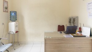 Et receptionsområde med skrivebord i træ, en bærbar computer, en vanddispenser og en stol.