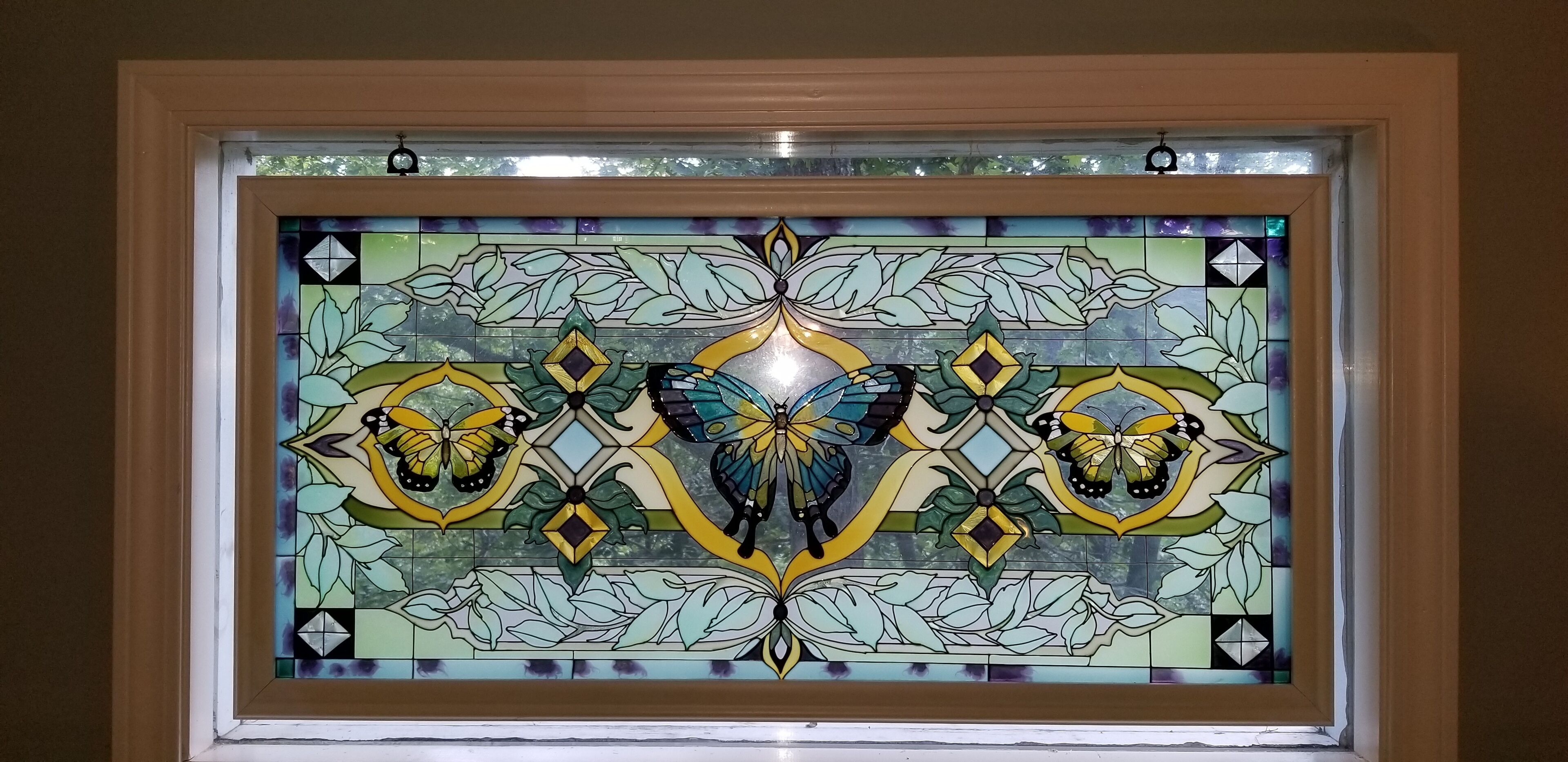 Een glas-in-loodraam met bloemen en vlinderontwerpen.
