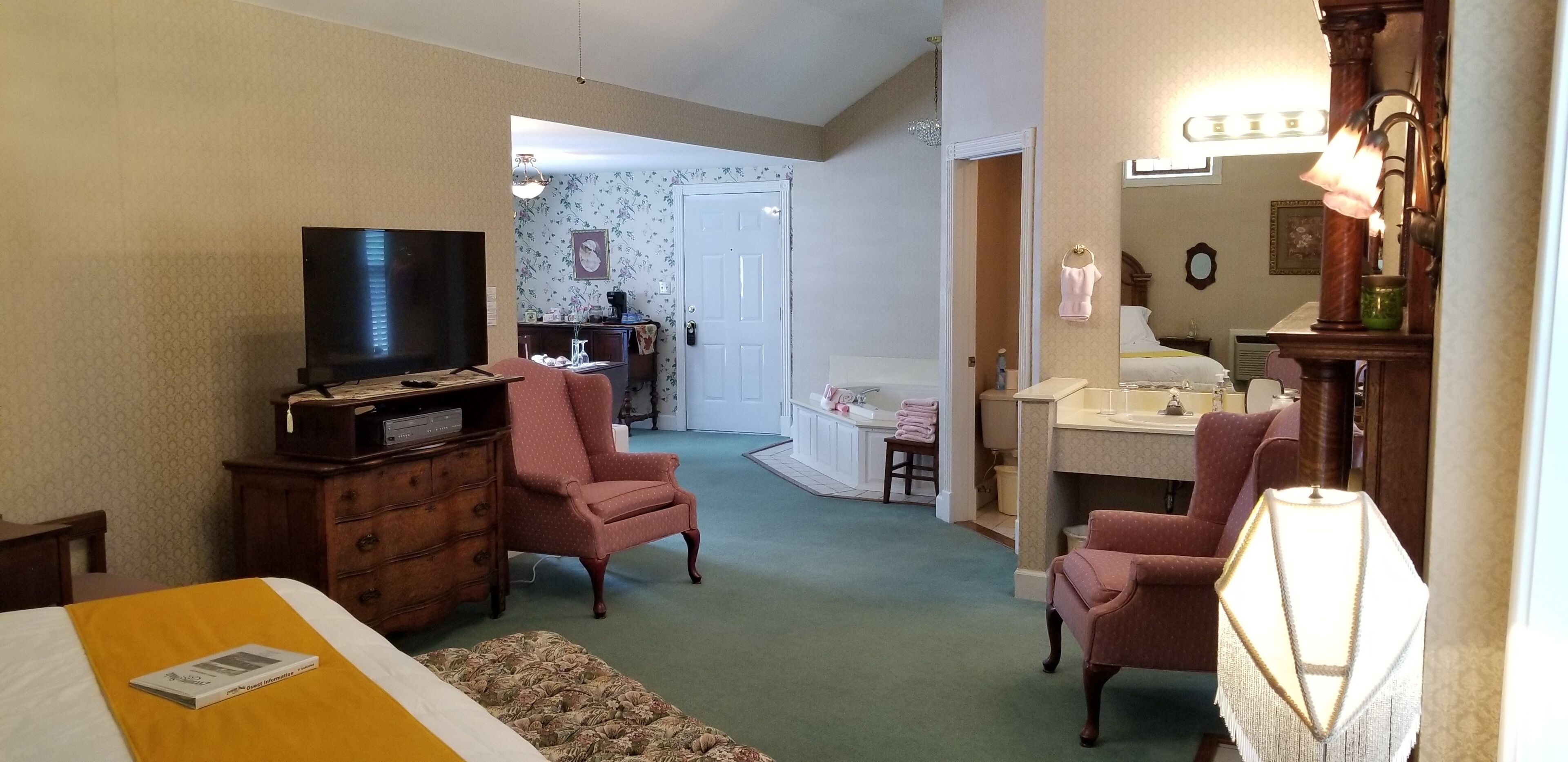 A room with a bed, a television, a desk, and two chairs.