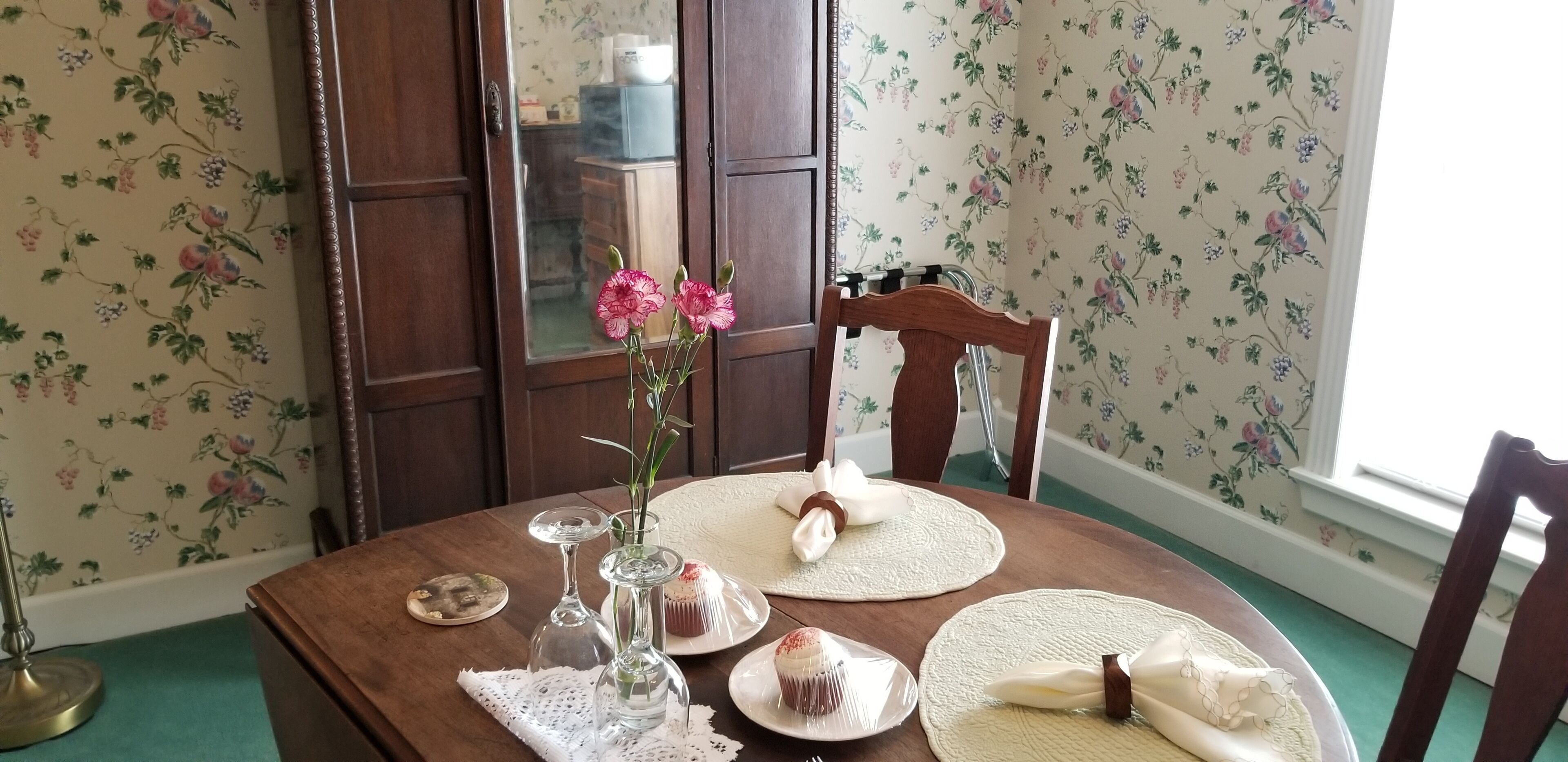 Une table à manger dressée avec des assiettes, un vase rempli de fleurs et une carafe en verre.