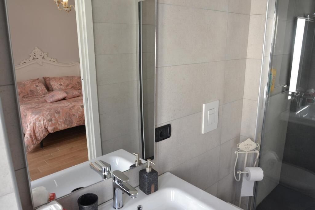 Un baño con un espejo grande, un lavabo, una ducha e inodoro.