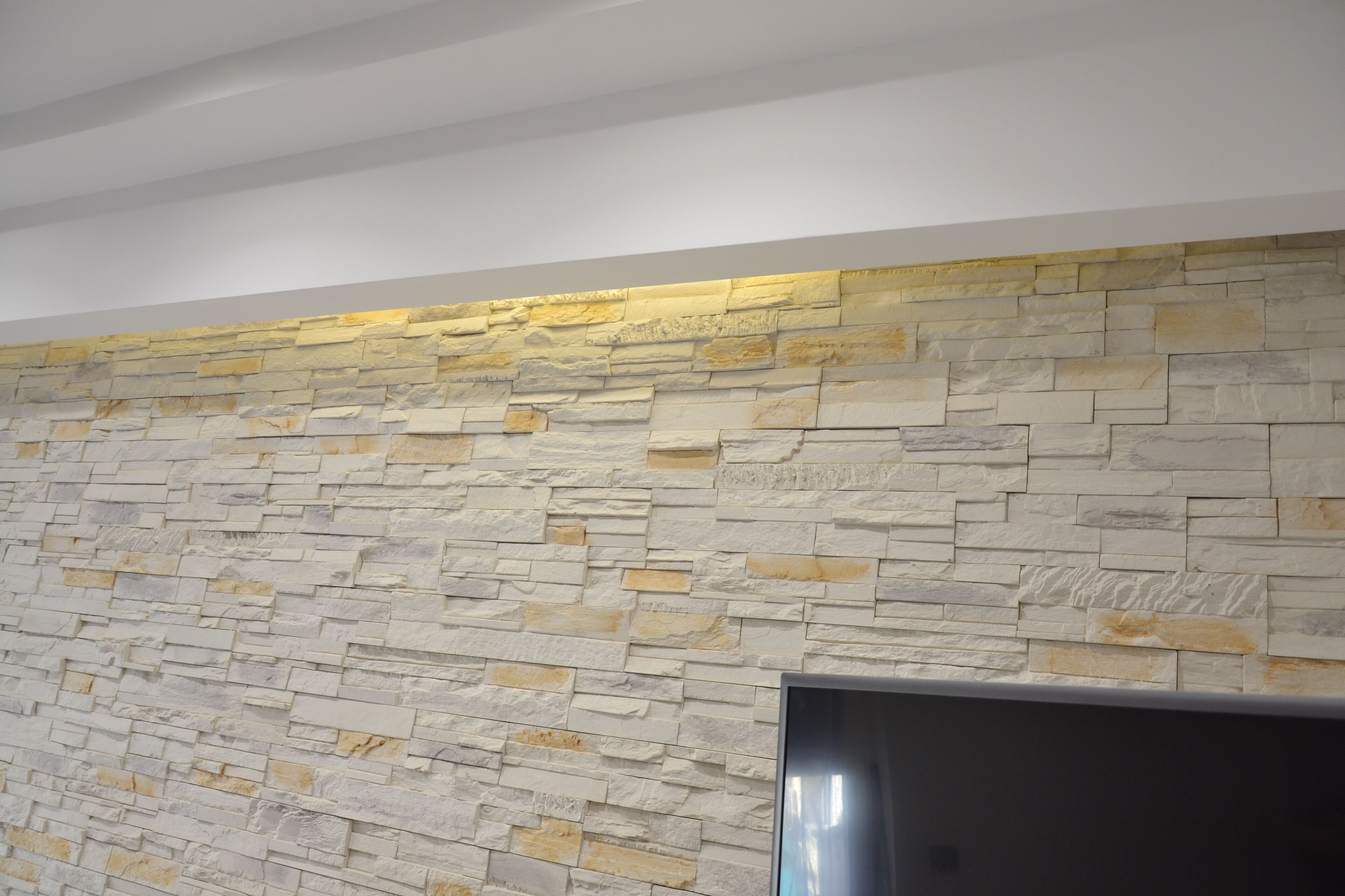 A stone wall with a flat-screen TV mounted on it.