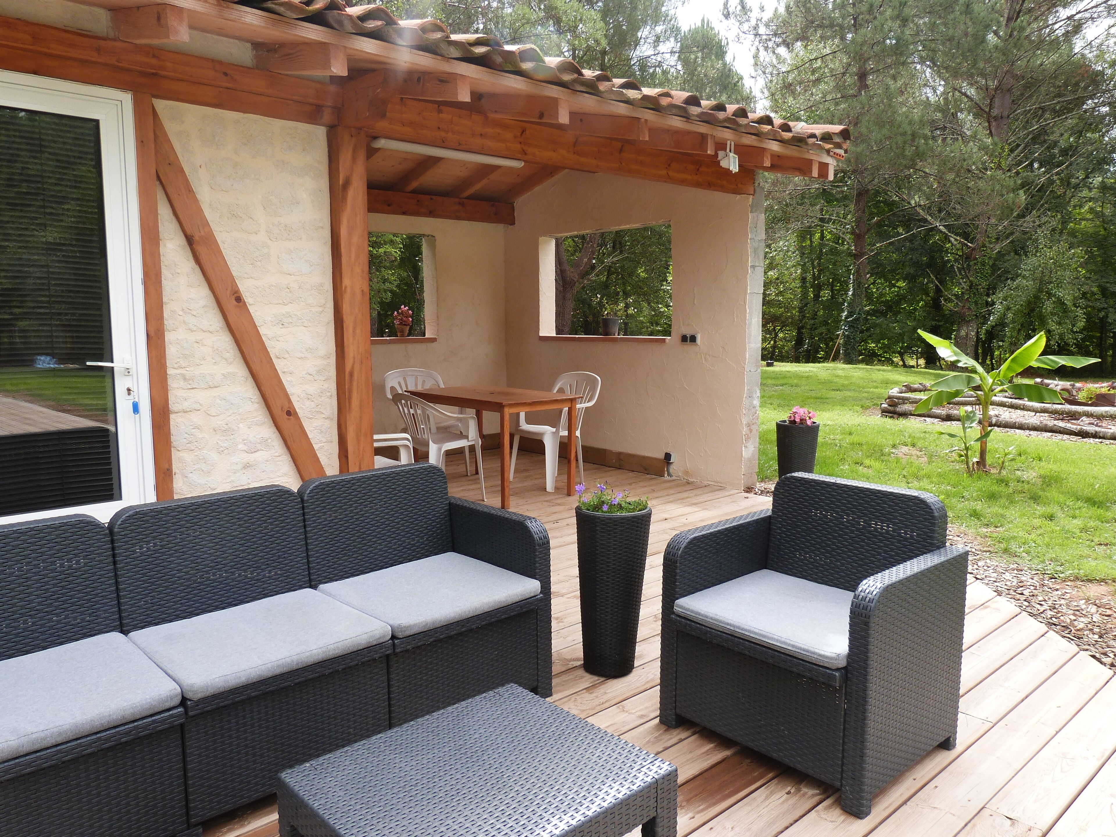 A covered outdoor patio with wicker furniture, a wooden table, and chairs.