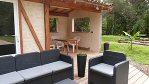 A covered outdoor patio with wicker furniture, a wooden table, and chairs.