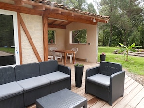 A covered outdoor patio with wicker furniture, a wooden table, and chairs.