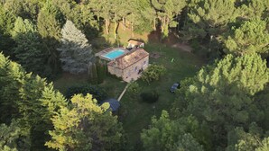 A house surrounded by dense forest, with a swimming pool and a small garden.