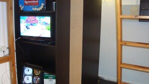 A room with a television on a wooden shelf, a DVD player, and a game titled "Rummikoo". - Studio accredits 3clés the slopes Centre station free wifi (Les Deux-Alpes)