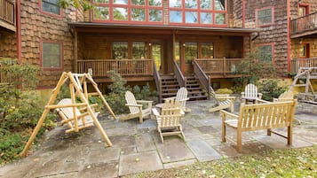 A cabin with a porch, outdoor seating, and a staircase leading to an upper level.
