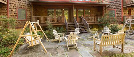 A cabin with a porch, outdoor seating, and a staircase leading to an upper level.