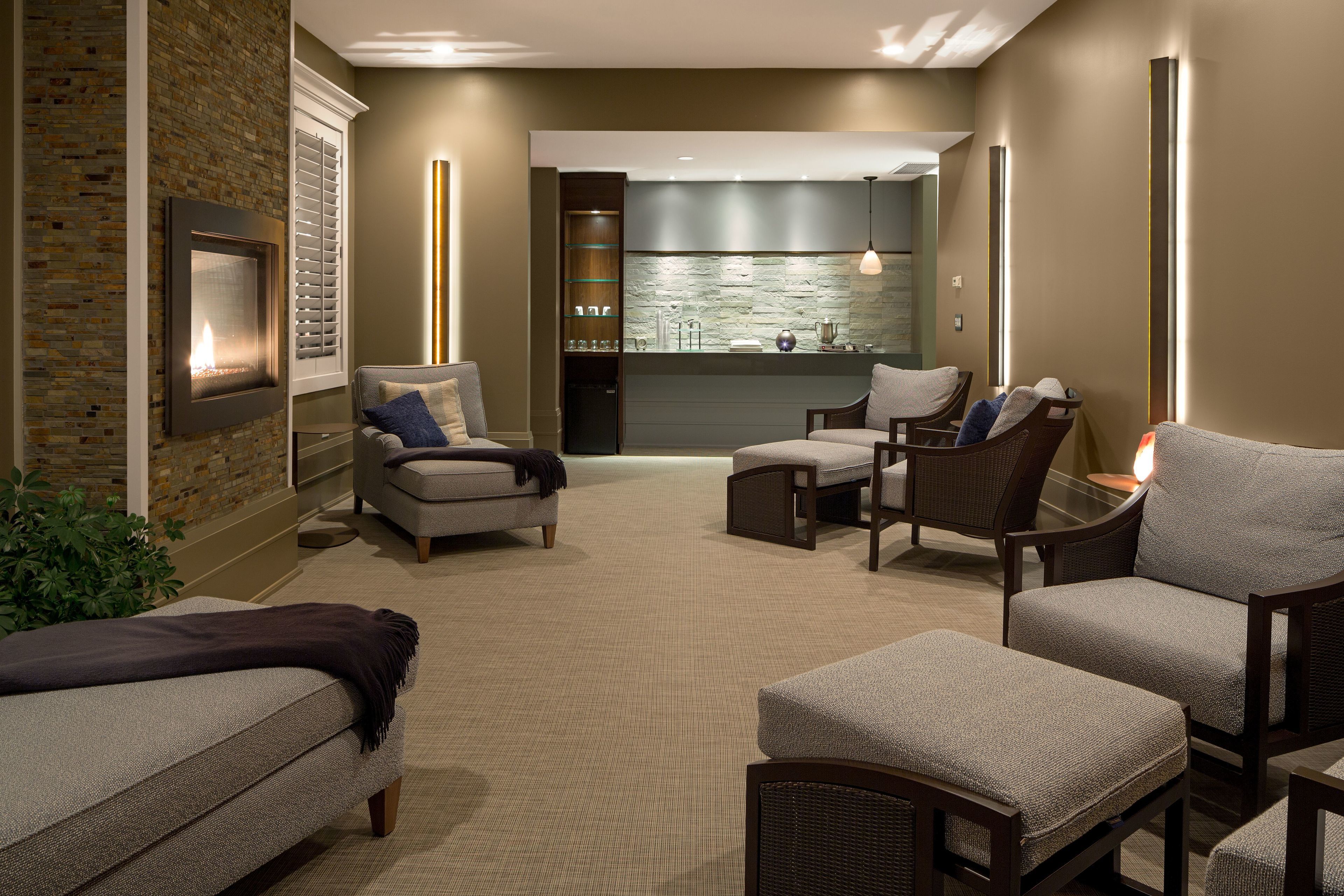 A modern living room with a fireplace, comfortable seating, and a kitchen area in the background.
