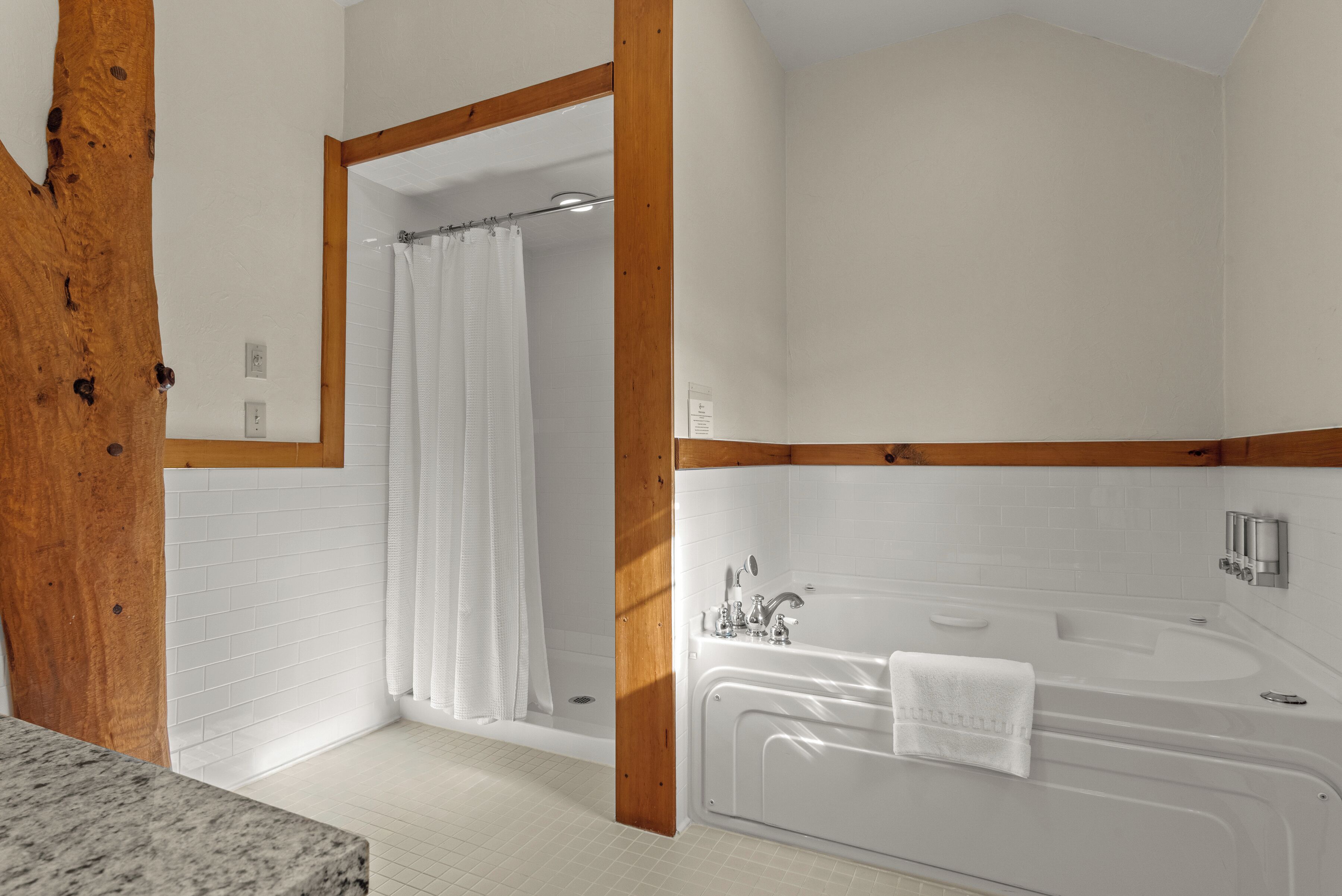 A bathroom with a bathtub, shower curtain, and wooden beams.
