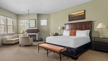 A bedroom with a large bed, a bench, a sofa, and a fireplace.