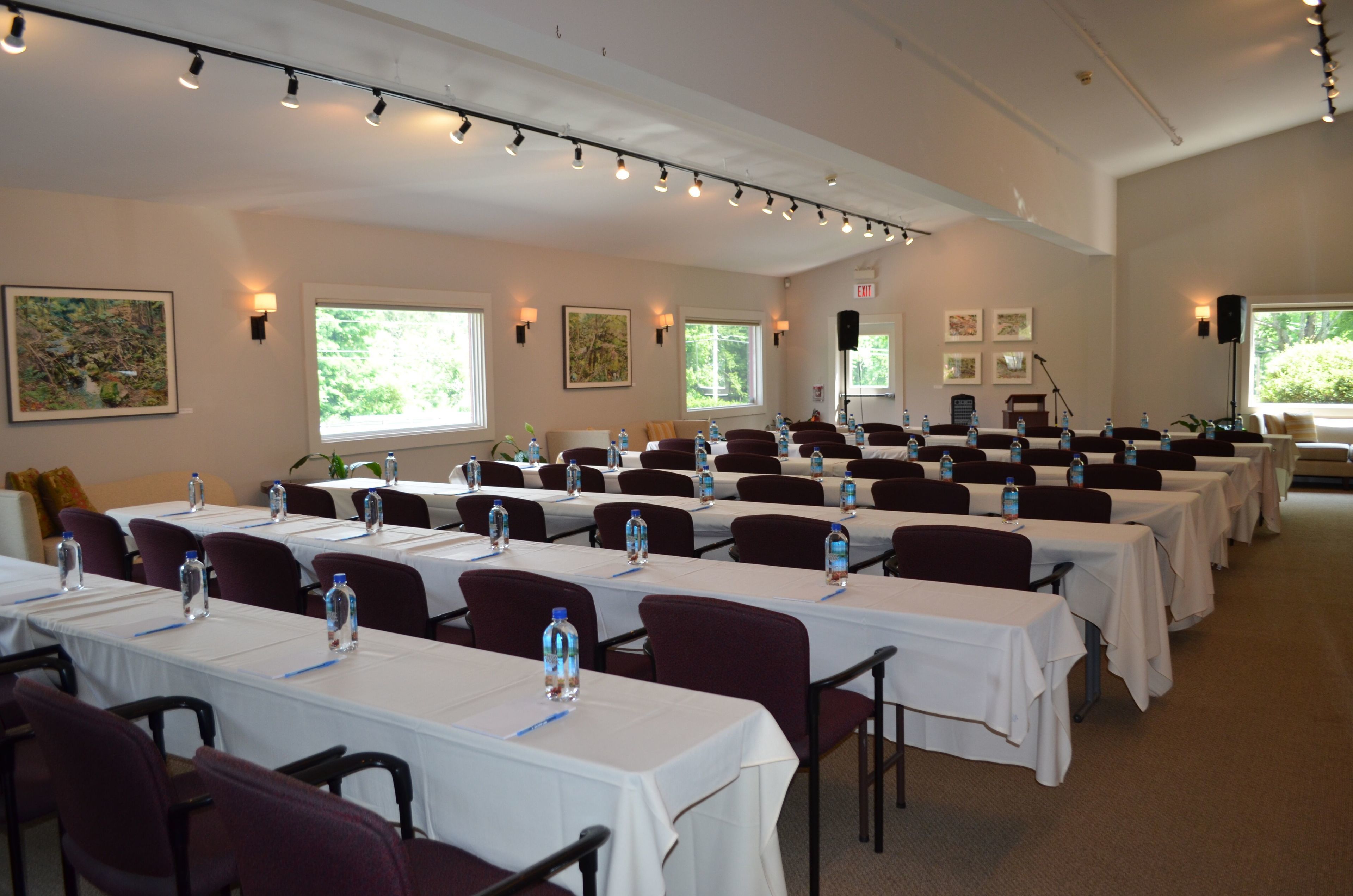 A conference room with rows of tables, chairs, and water bottles.