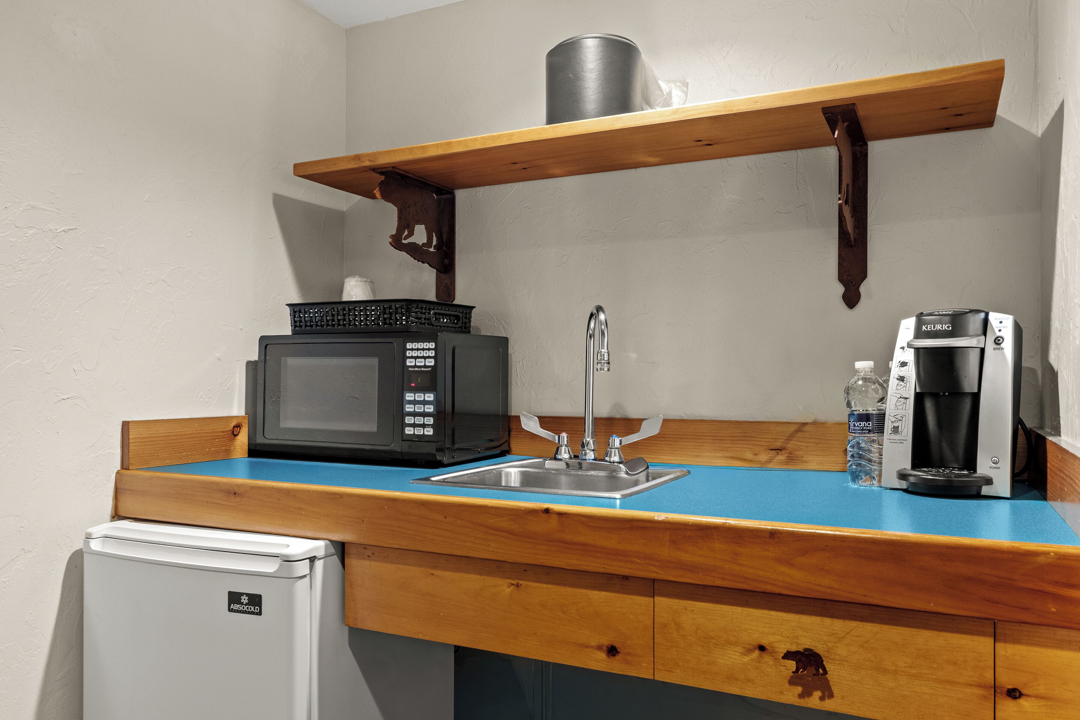 Una kitchenette equipada con microondas, cafetera y un refrigerador pequeño.