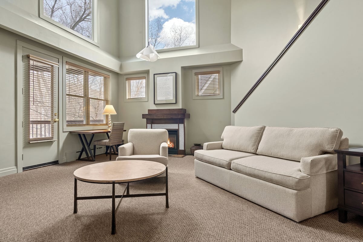 A living room with a fireplace, a sofa, a round table, and a lamp.