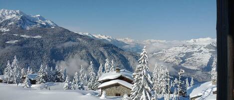A snow-covered mountain landscape with wooden cabins and snow-laden trees.