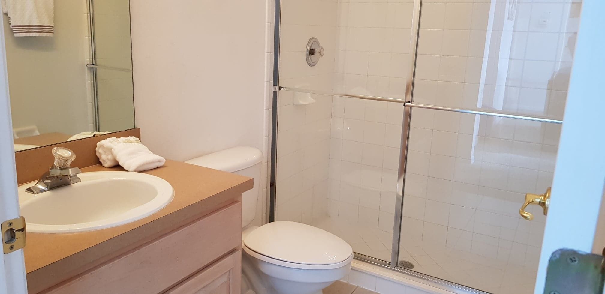 A bathroom with a sink, toilet, and glass shower enclosure.