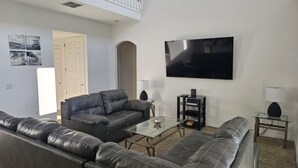 A modern living room with a sectional sofa, a coffee table, a TV, and a small side table. - 5 Bedroom family home in gated community, near Disney. (Davenport)