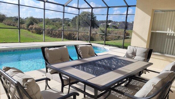 A covered patio with a pool, outdoor furniture, and a view of the surrounding landscape. - 5 Bedroom family home in gated community, near Disney. (Davenport)