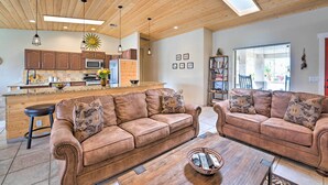 Un vaste espace de vie agrémenté d’un plafond en bois, une cuisine équipée d’appareils électroménagers modernes et un coin salon confortable.