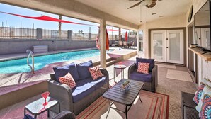 Un espace aménagé au bord de la piscine, avec des meubles en osier, un ventilateur de plafond et une vue sur la piscine.